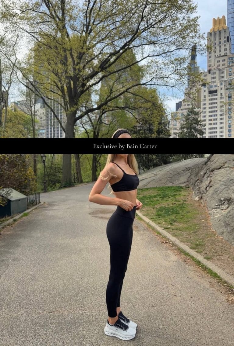 Blonde woman wearing a black sports outfit standing in a city park