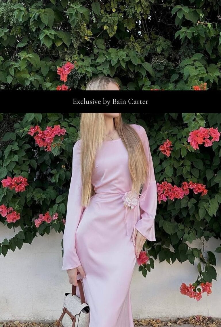 Woman wearing a long pink dress standing in front of flowering plants