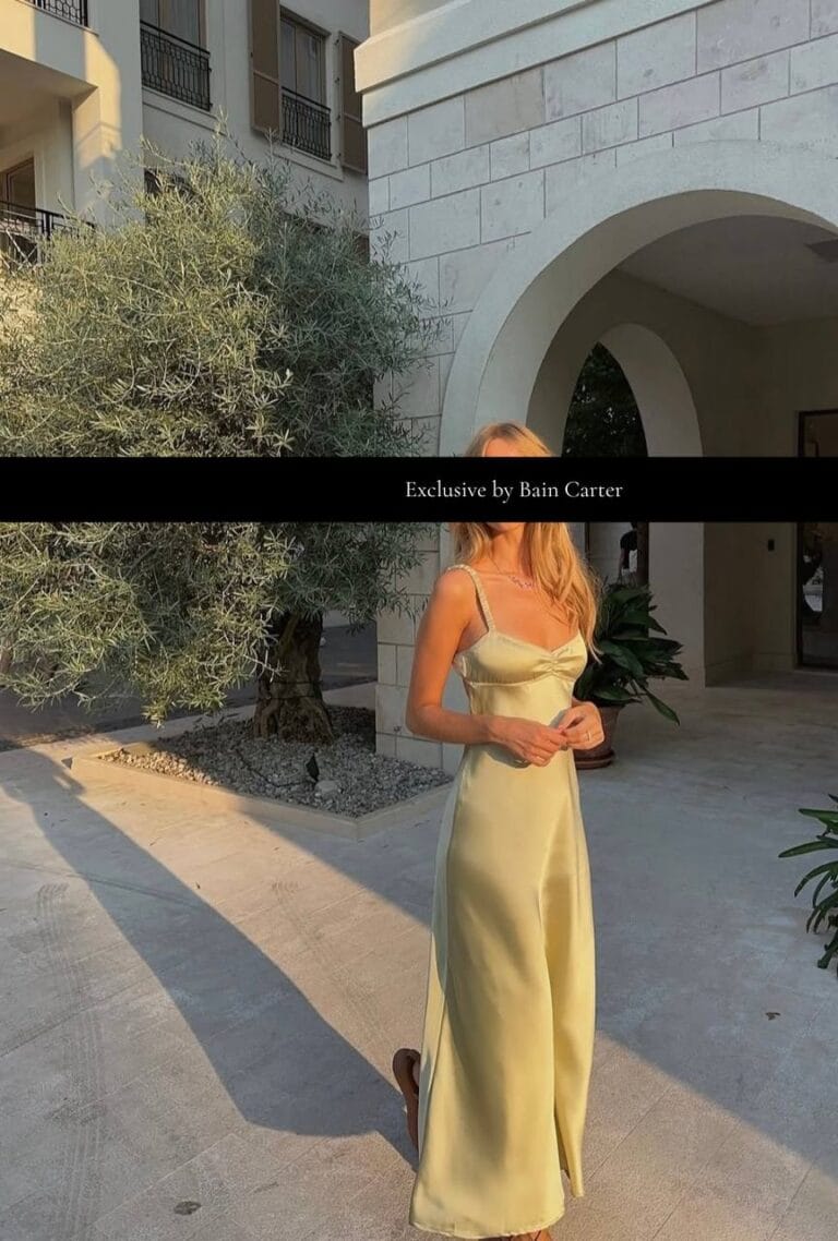 Blonde woman wearing a light green dress standing beneath a stone archway