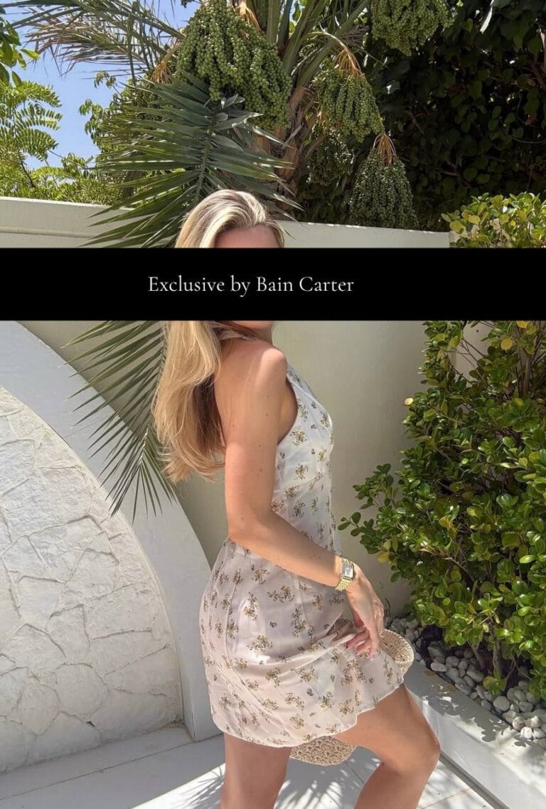 Woman wearing a light floral dress standing beside palm trees