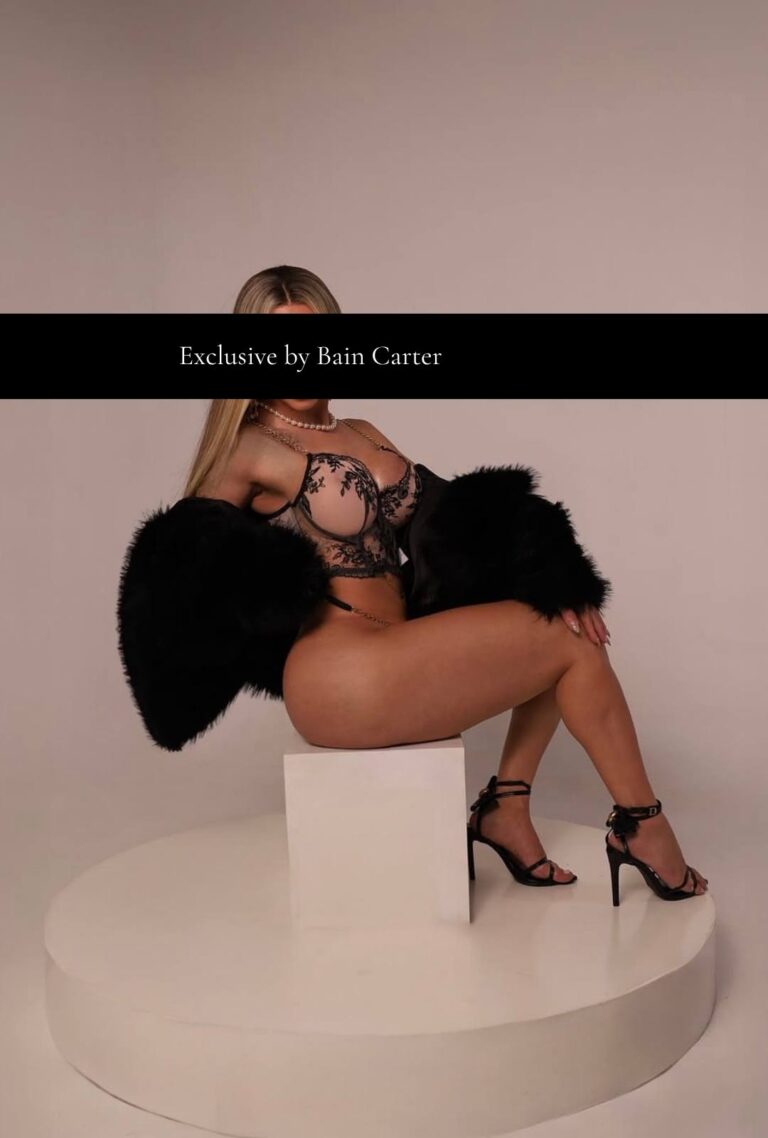Génesis sentada con lencería negra y tacones