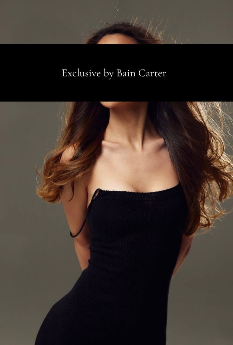 Catarina posing in a fitted black dress with her hair over her shoulders