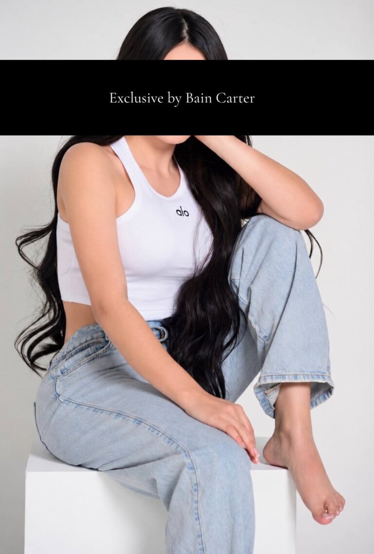 Gabriella sitting in light blue jeans and a white crop top during a photoshoot