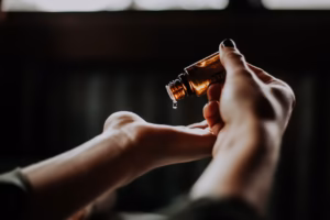 Manos aplicando aceite de masaje sobre la palma en un ambiente íntimo.